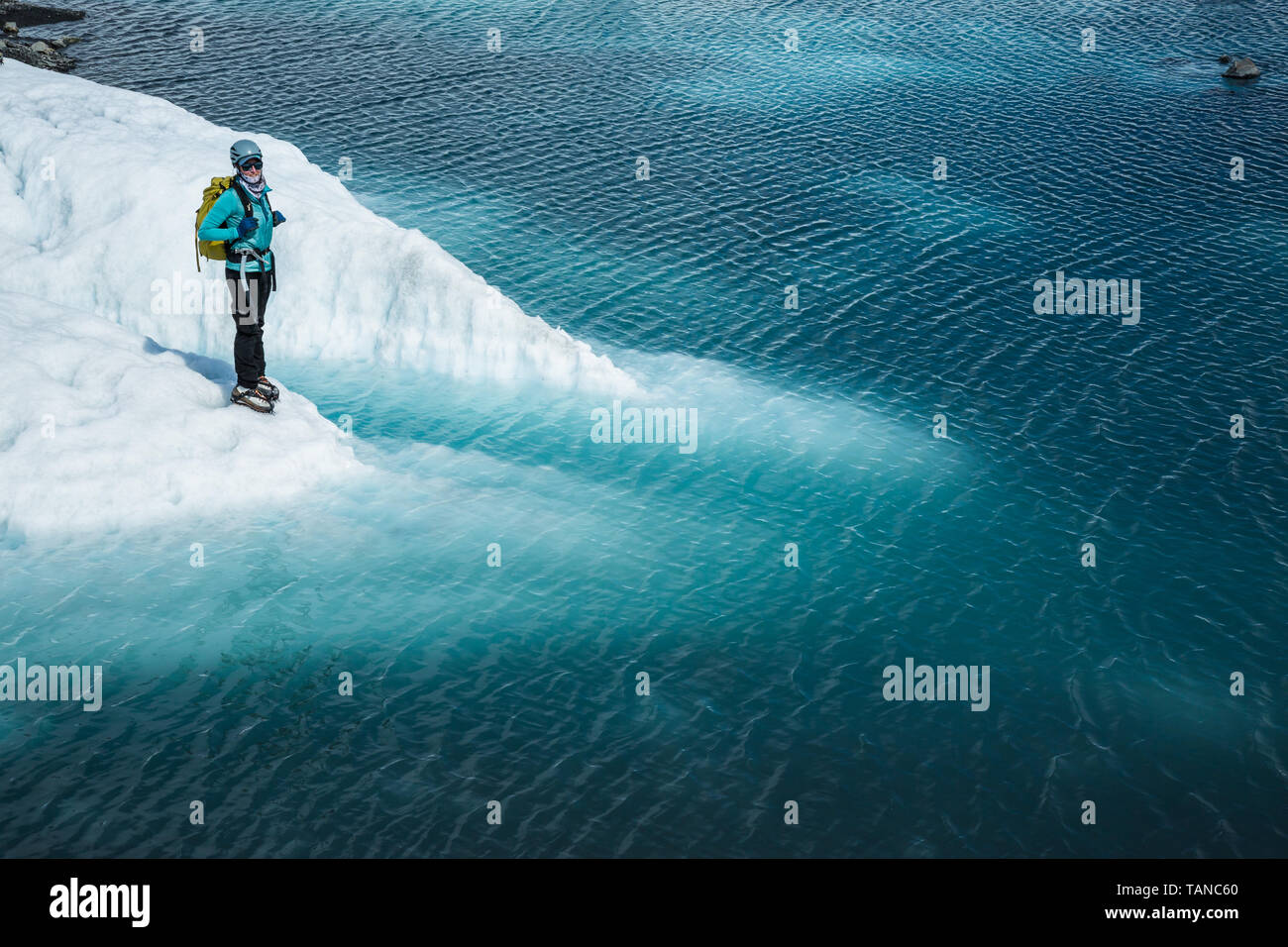 Une femme debout avec un casque et un pack près du bord d'un lac bleu. Le lac est sur le dessus de la Matanuska glacier des montagnes Chugach, de l'EC Banque D'Images