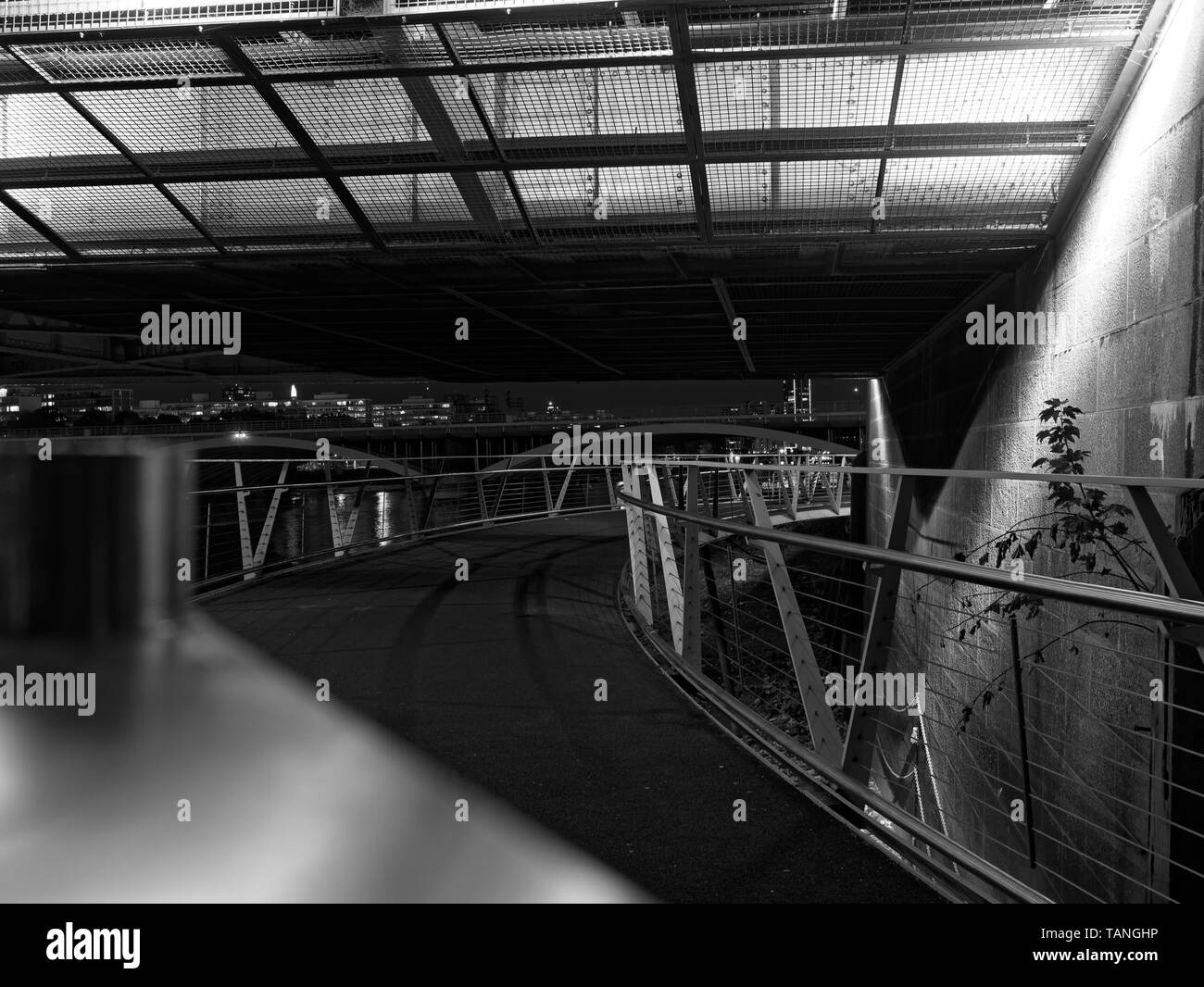 Vue en perspective de passerelle pour piétons au-dessus de la Tamise avec une clôture en acier et garde-corps dans la nuit. Image en noir et blanc. Les ponts et la rivière Banque D'Images