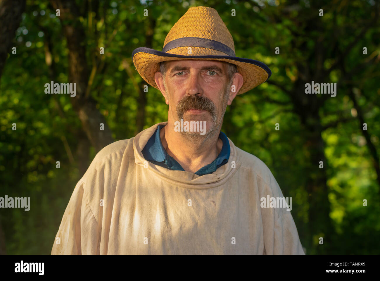 Portrait d'apiculteur fatigué wearing straw hat et sale chemise en lin sur le lieu de travail Banque D'Images