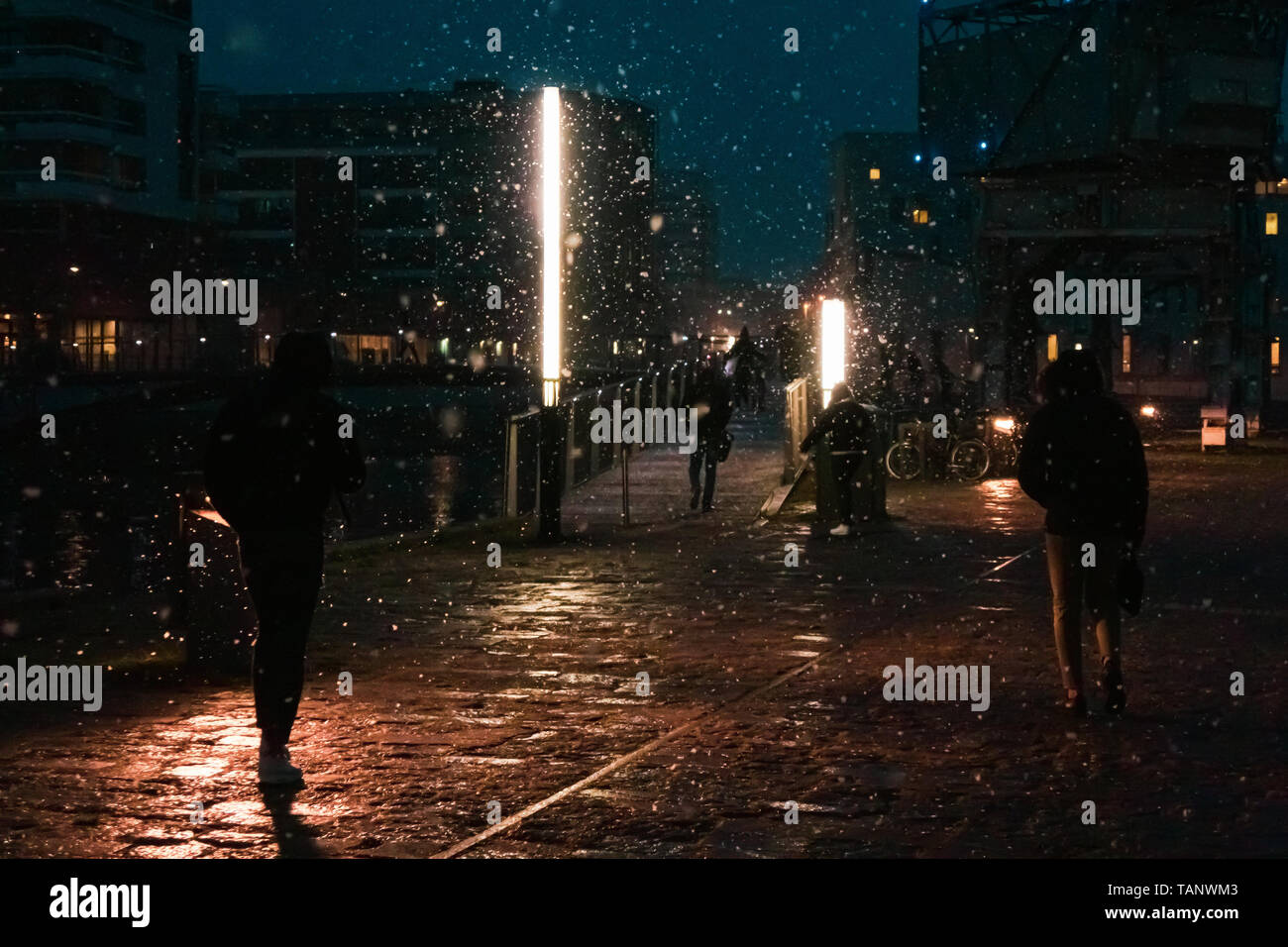 Scène urbaine de nuit avec des gens qui marchent pendant une tempête. Banque D'Images