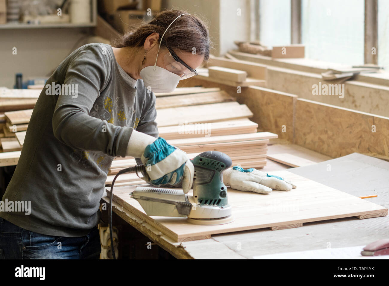 Jeune femme moud35 avec la machine de meulage angulaire en atelier Banque D'Images