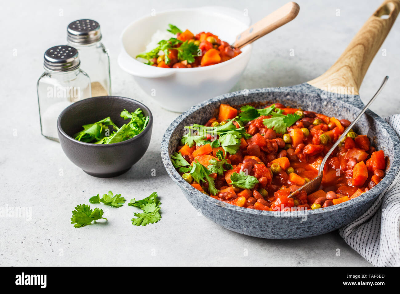 Ragoût de haricots végétalien avec des tomates et le riz dans une casserole à fond blanc. La nourriture végane concept. Banque D'Images