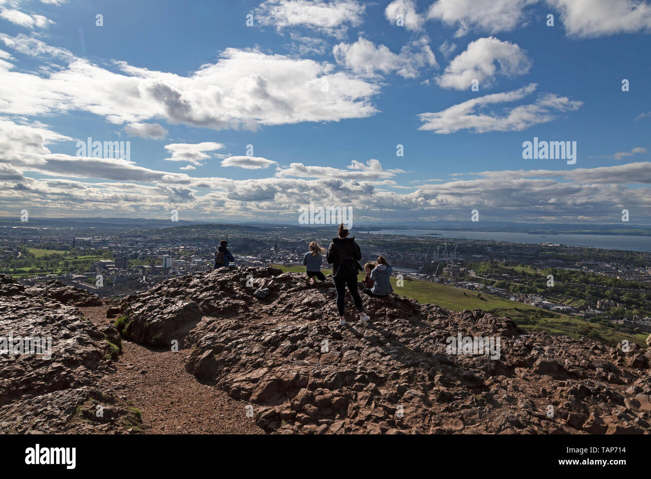 Un groupe de touristes à la recherche vers le bas sur la ville d'Edimbourg en Ecosse, de l'ancien fort de colline de l'emplacement de Arthur's Seat. Banque D'Images