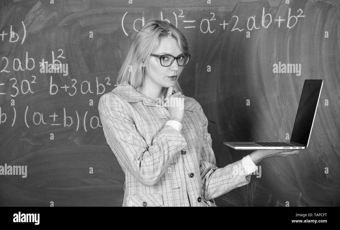 Enseignante portent des lunettes est titulaire d'ordinateur portable Internet surf. L'éducation scolaire de base. Les technologies numériques concept. Smart éducateur dame avec ordinateur portable moderne tableau internet surf arrière-plan. Banque D'Images