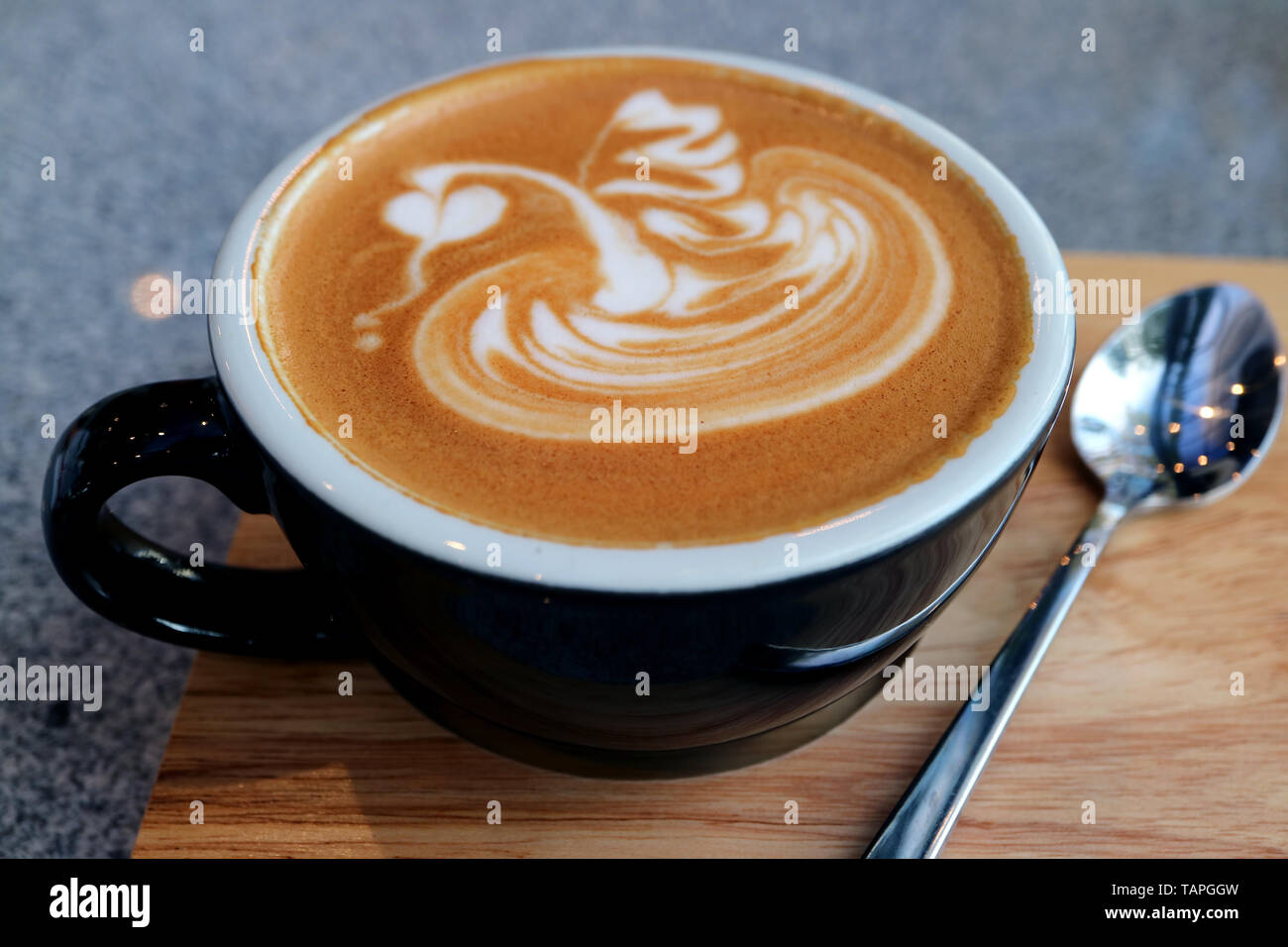 Libre une tasse de Cappuccino avec cuillère à café servi sur plateau en bois Banque D'Images