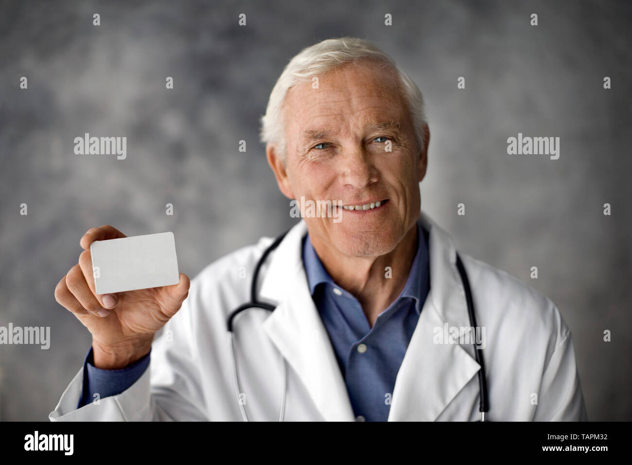 Smiling doctor holding up a carte blanche. Banque D'Images