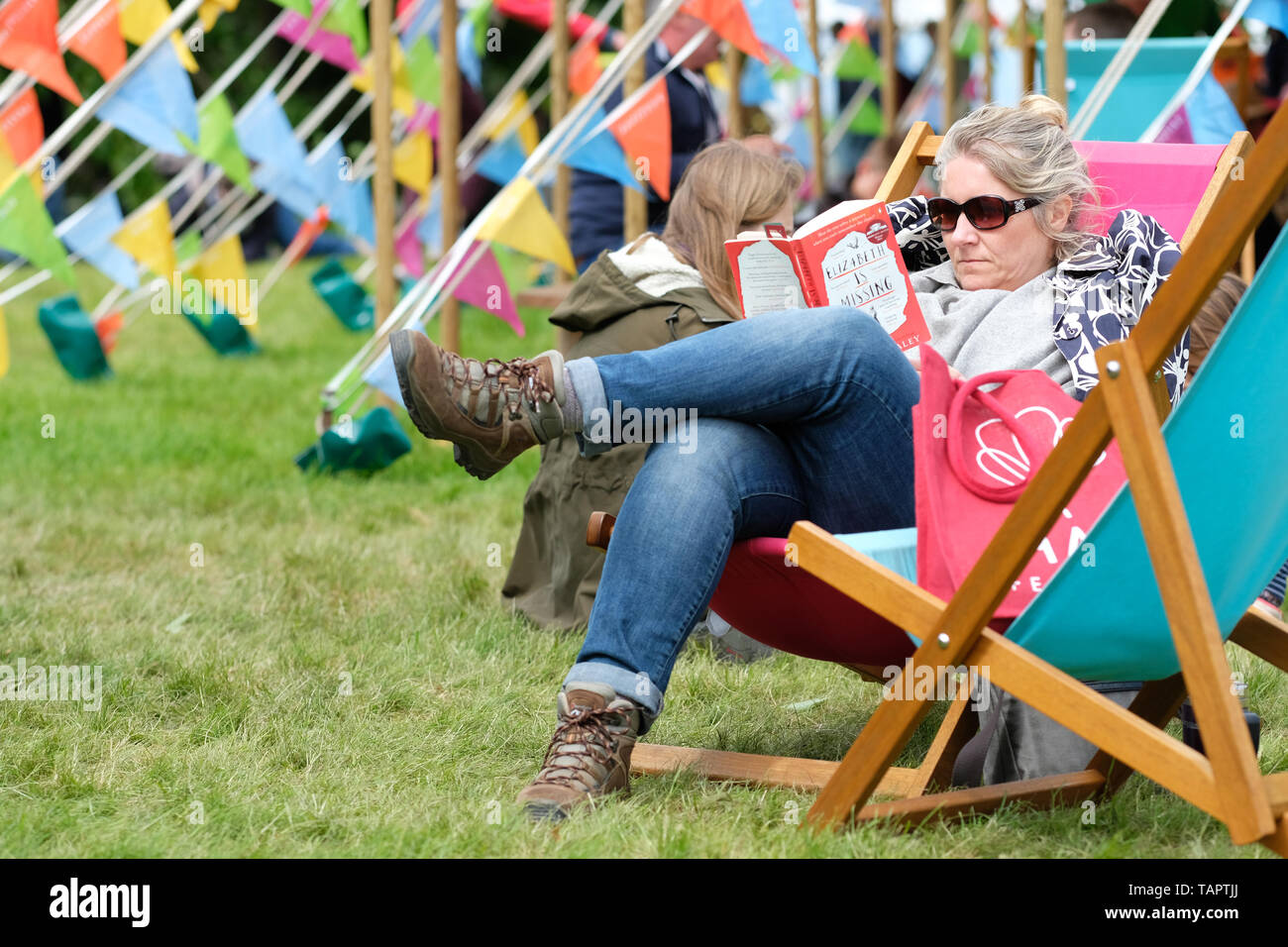 Hay Festival, Hay on Wye, Powys, Wales, UK - Lundi 27 mai 2019 - un visiteur bénéficie d'une chance de lire sur les pelouses du Festival entre les événements et les haut-parleurs à l'Hay Festival lors d'une fraîche sunny breezy Bank Holiday lundi. Photo Steven Mai / Alamy Live News Banque D'Images