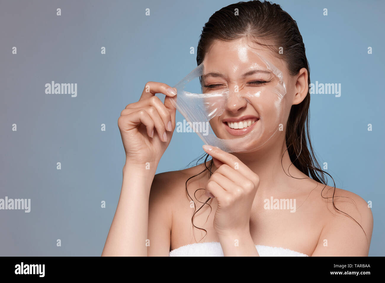 Happy woman avec son masque facial de dureté et souriante, jolie jeune fille faisant procédures spa, copy space Banque D'Images