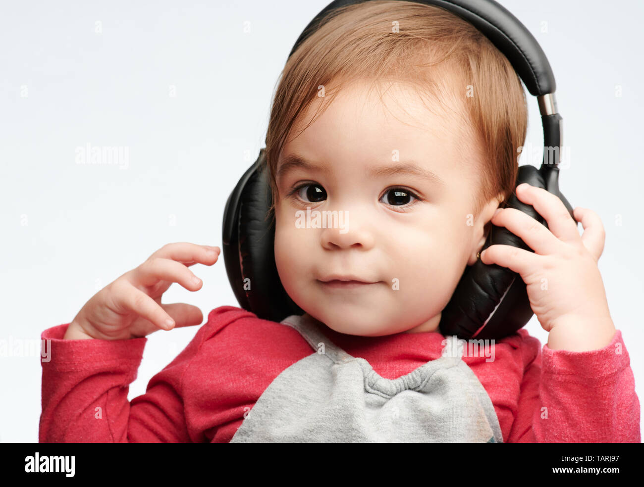 Baby Girl écouter de la musique avec des écouteurs sur isolé sur fond blanc Banque D'Images