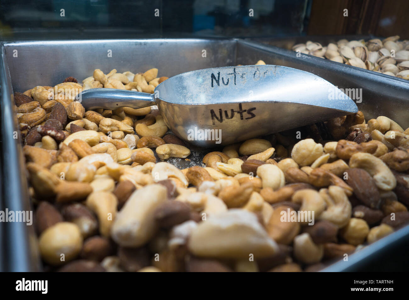 Un bac rempli de différents types de noix et d'une écope d'argent avec le mot 'noix' écrit dessus Banque D'Images