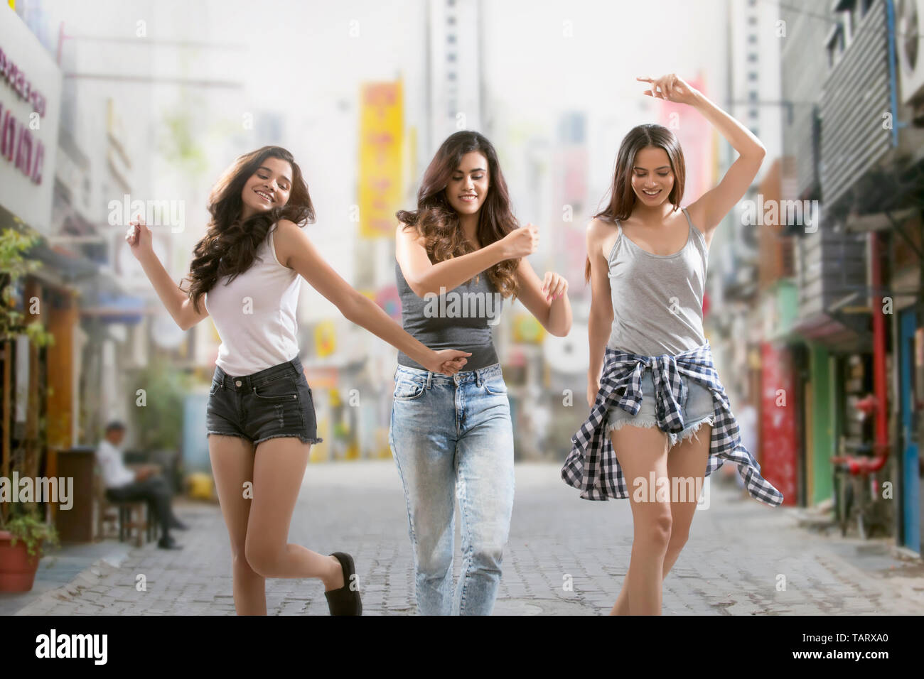 Trois girl friends dancing on street Banque D'Images