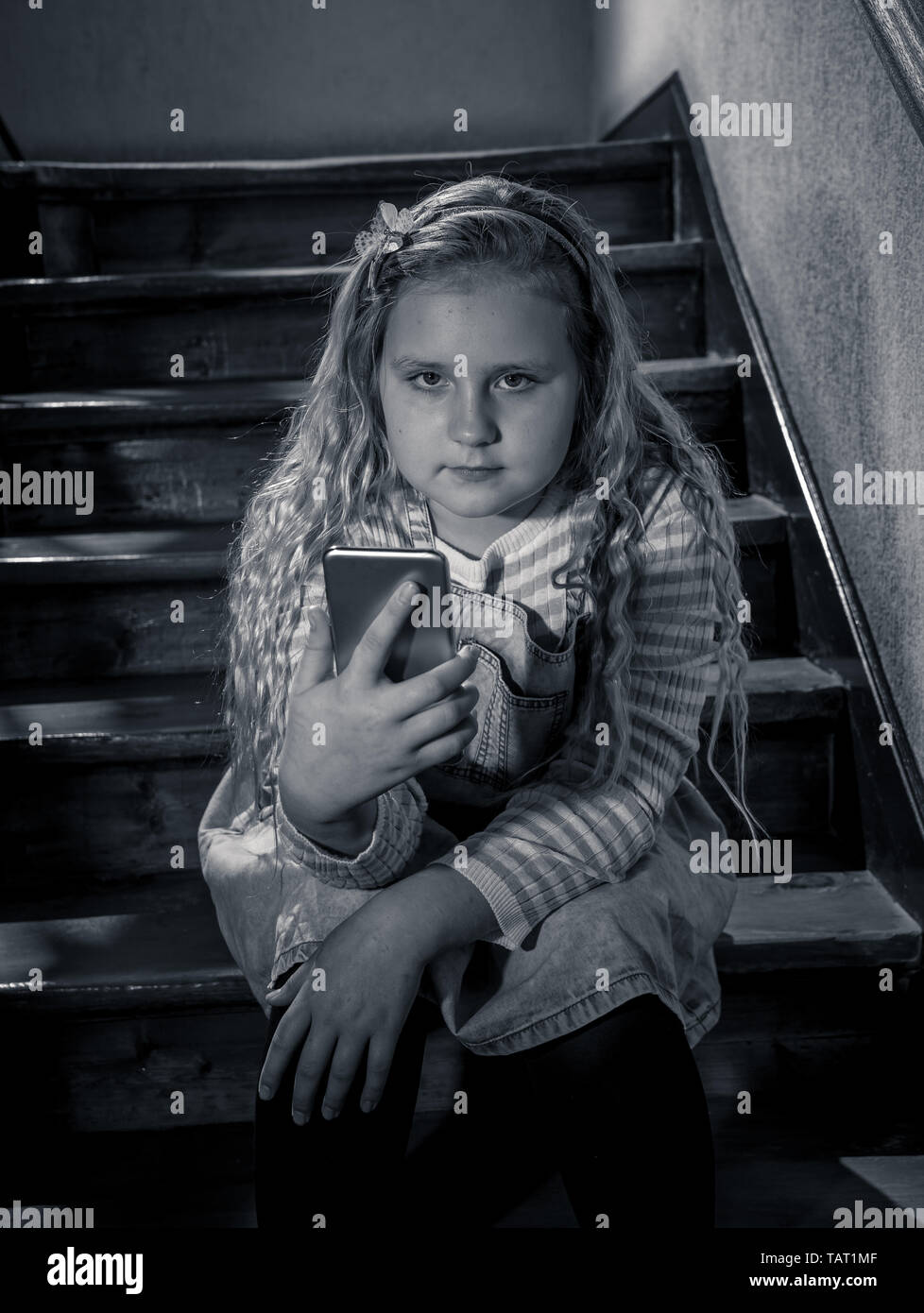Déprimé triste jeune fille victime de cyberintimidation par smart mobile phone sitting on stairs vous sentir seul, malheureux, sans espoir et d'abus. Un enfant intimidé Banque D'Images
