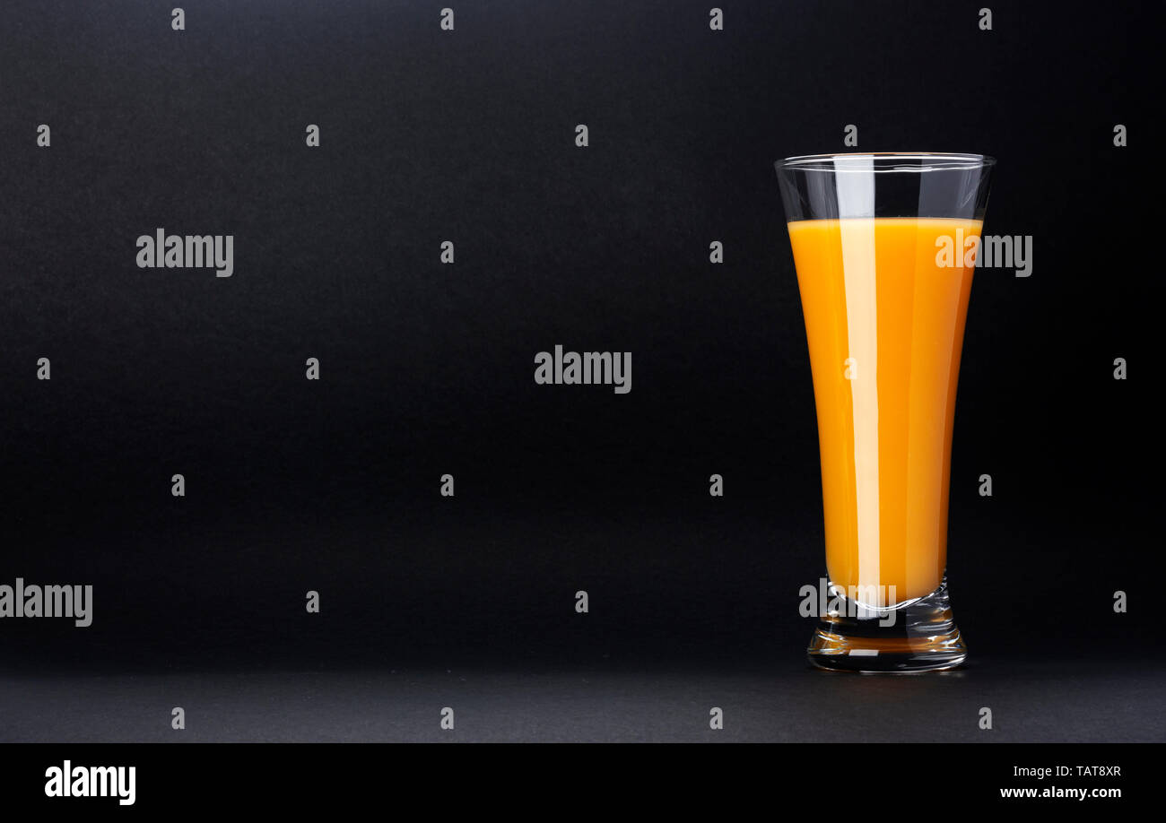 Verre de jus d'orange isolé sur fond noir avec copie espace pour texte, cocktail d'agrumes frais Banque D'Images