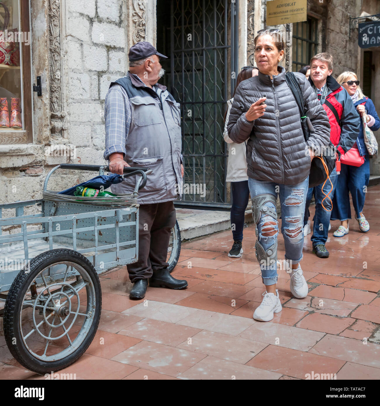 Le Monténégro, 30 avril 2019 : scène de rue avec des homme debout à côté d'un tricycle de livraison et les touristes se promener dans la vieille ville de Kotor Banque D'Images