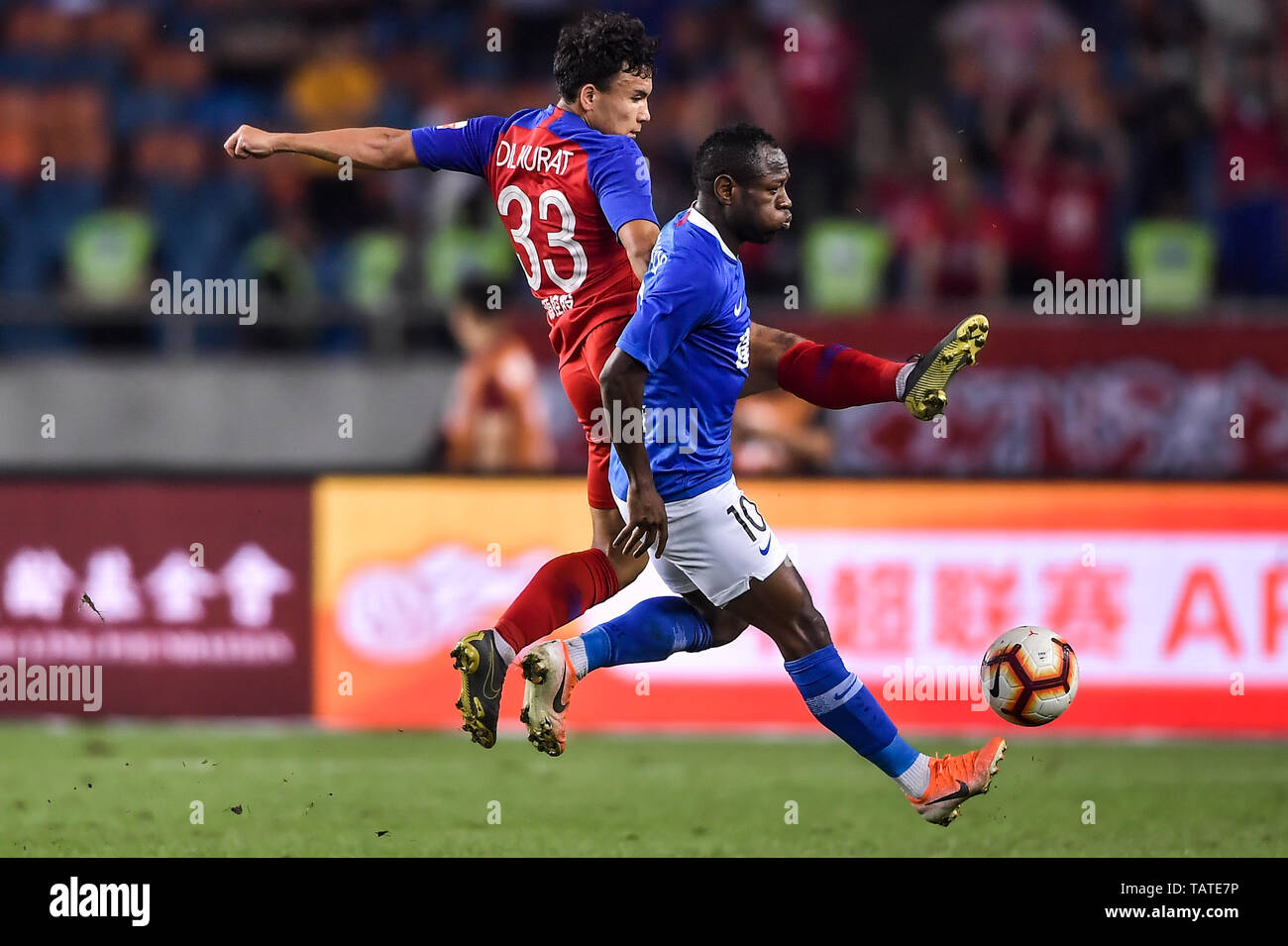 Joueur de football camerounais Christian Bassogog, droite, de Henan Jianye  passe le ballon contre un joueur de Chongqing GDS en leur 11e match au  cours de l'Association de football chinoise 2019 Super