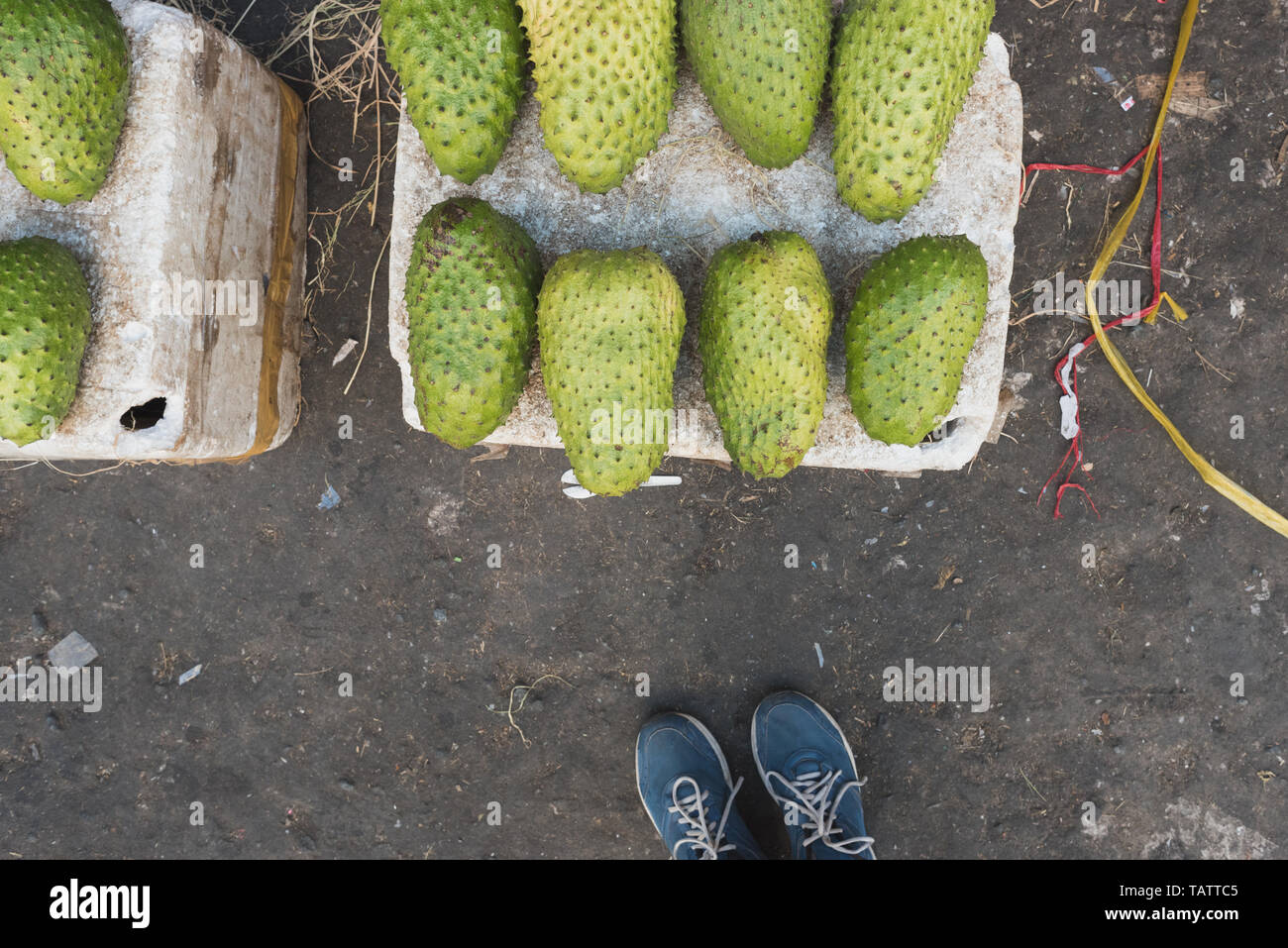 Fruits de corossol (Annona muricata) sur les étals de polystyrène s'effondrer sur le sol sale au marché Binh Tay Cho à Ho Chi Minh City, Vietnam. Banque D'Images