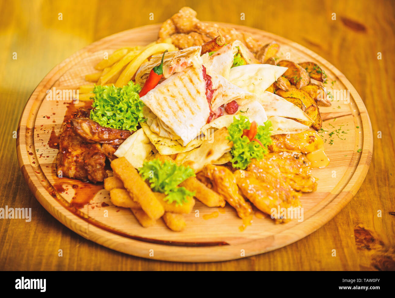 De délicieux en-cas savoureux. Snack pour la bière. Les repas au restaurant. Planche de bois avec beaucoup de frites et bâtonnets de poisson viande burrito steak servi avec une salade. Calories élevé pour le groupe d'amis. Menu snack-bar. Banque D'Images