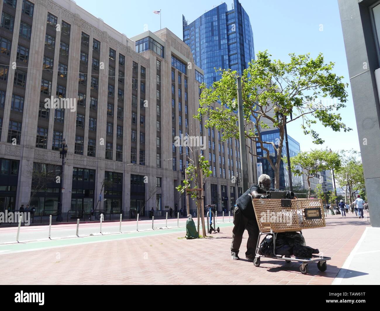 San Francisco, USA. 10 mai, 2019. Un sans-abri guy pousse un panier avec ses affaires le long de Market Street. Le siège de Twitter est dans l'arrière-plan. Le boom technologique dans la région de San Francisco et Silicon Valley voisins a fourni à la région avec des dizaines de milliers d'emplois et de nombreux nouveaux millionnaires. L'inconvénient : l'explosion des loyers et sans-abri dans les rues. La vie dans cette ville profondément divisé devient inestimable. (Dpa 'milliardaires et la pauvreté : les grands groupes quake tech San Francisco' du 26.05.2019) Crédit : Barbara Munker/dpa/Alamy Live News Banque D'Images