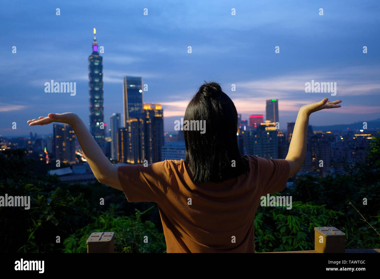 Une femme qui se pose contre les gratte-ciel de Taipei City au crépuscule de Montagne d'éléphant ou Xiangshan (ou sentier de randonnée du quartier de Nangang) Dans le district de Xinyi Taipei Taiwan Banque D'Images