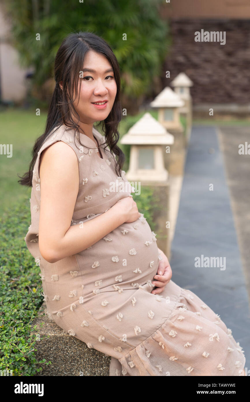 Belle asiatique femme enceinte au repos dans l'arrière-plan le jardin. Banque D'Images