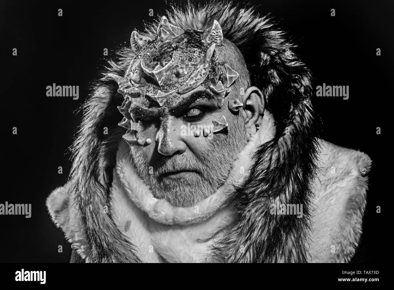 Concept arts sombres. Man avec barbe blanche habillé comme Monster. Démon sur fond noir, Close up. Homme d'épines ou verrues en manteau de fourrure. Alien, Banque D'Images