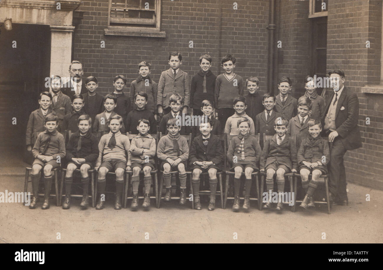 Vintage Carte postale photographique montrant un groupe de garçons de l'école britannique et leurs enseignants. Banque D'Images