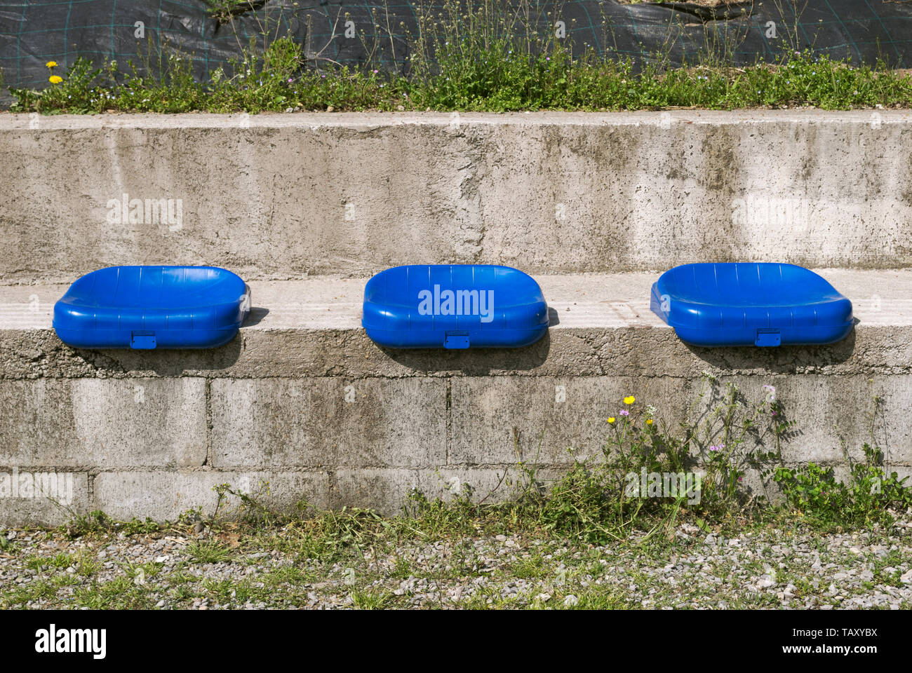 Sièges en plastique bleu monté sur le béton Banque D'Images