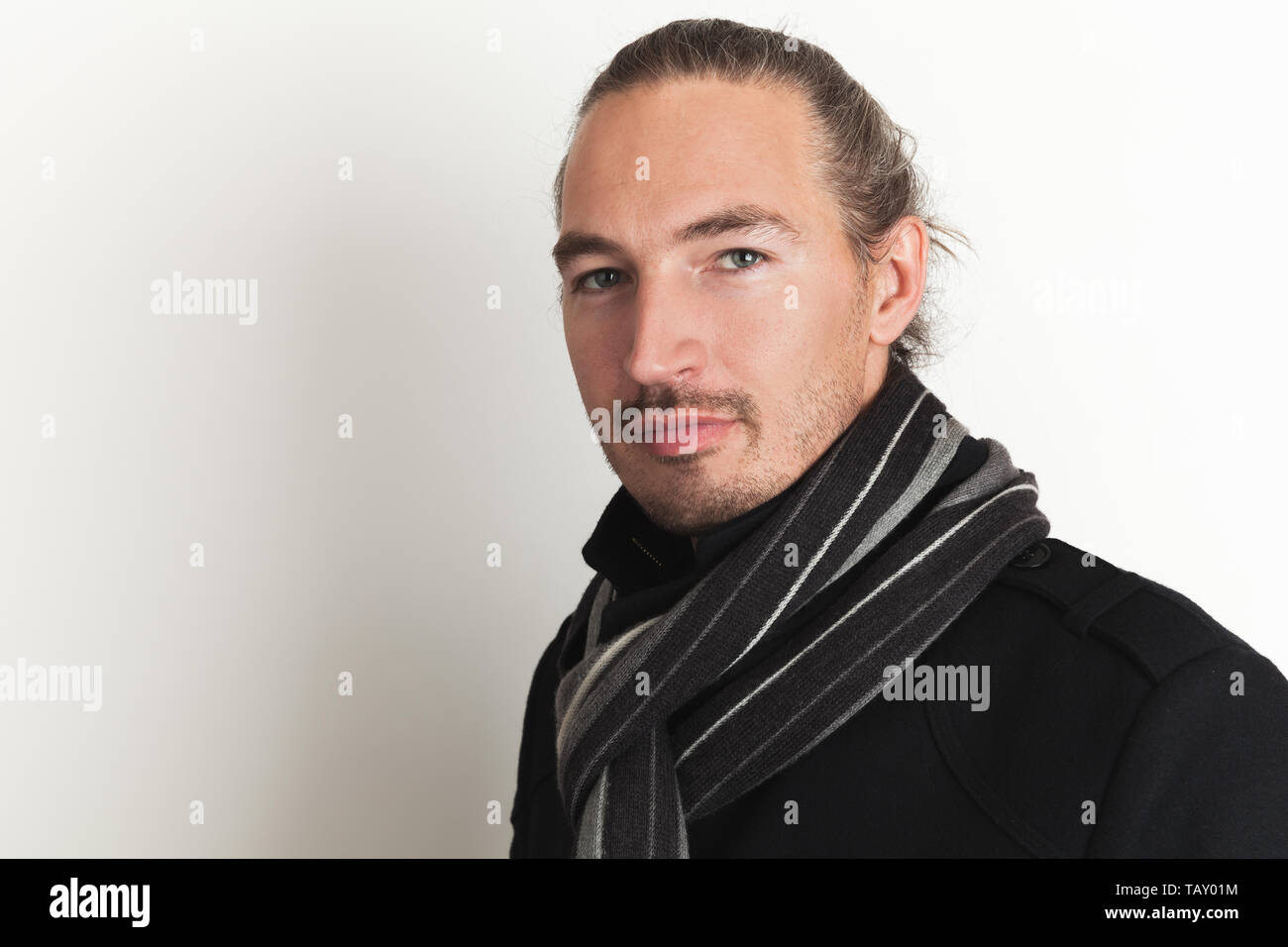 Jeunes adultes positifs Asian man en manteau noir et écharpe en laine se tient sur mur blanc arrière-plan. Close up studio portrait Banque D'Images