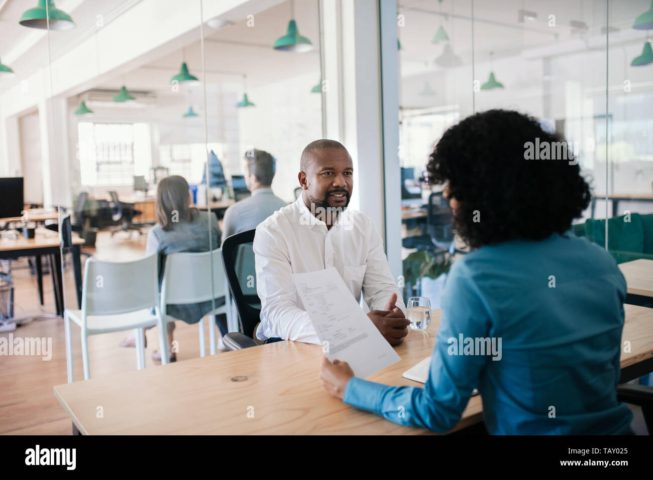African American man smiling en répondant à des questions au cours d'un entretien avec un manager in a modern office Banque D'Images