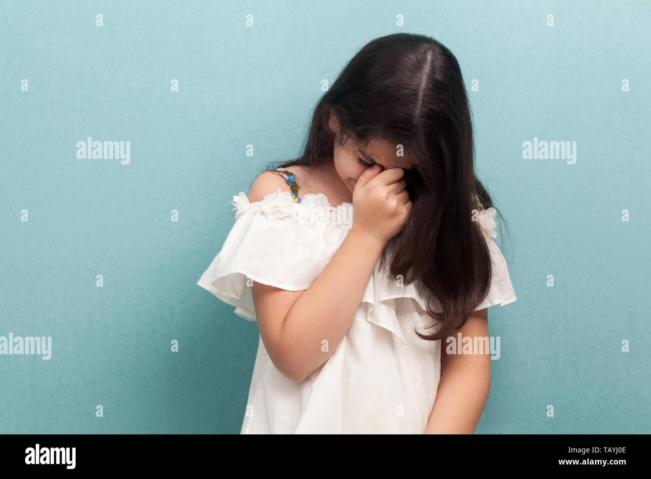 Portrait de triste malheureux belle brune jeune fille avec de long cheveux noir en robe blanche debout et pleurer. Piscine studio shot isolé sur Banque D'Images