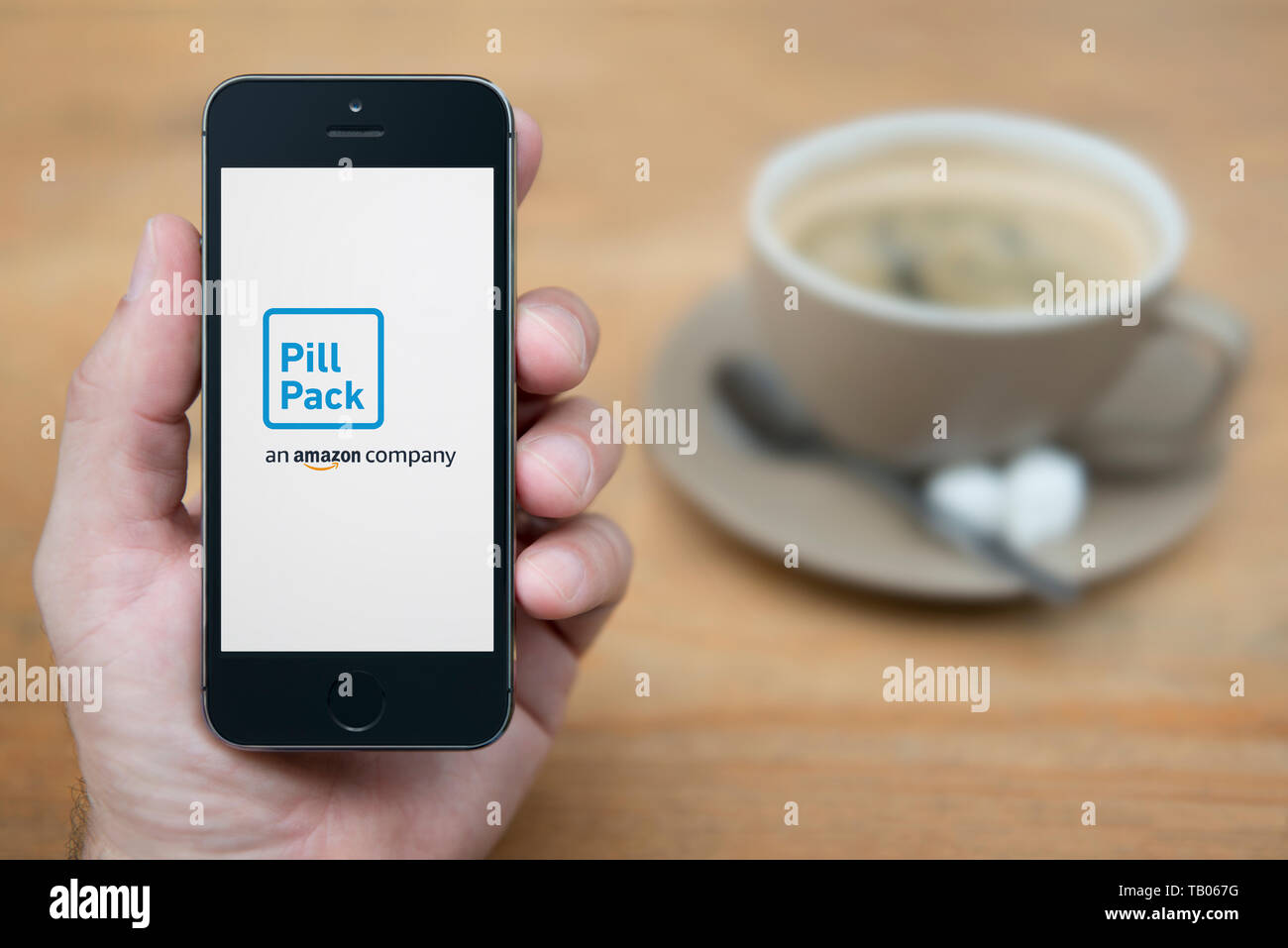 Un homme se penche sur son iPhone qui affiche le logo d'PillPack (usage éditorial uniquement). Banque D'Images Un homme se penche sur son iPhone qui affiche le logo d'PillPack (usage éditorial uniquement). Banque D'Images
