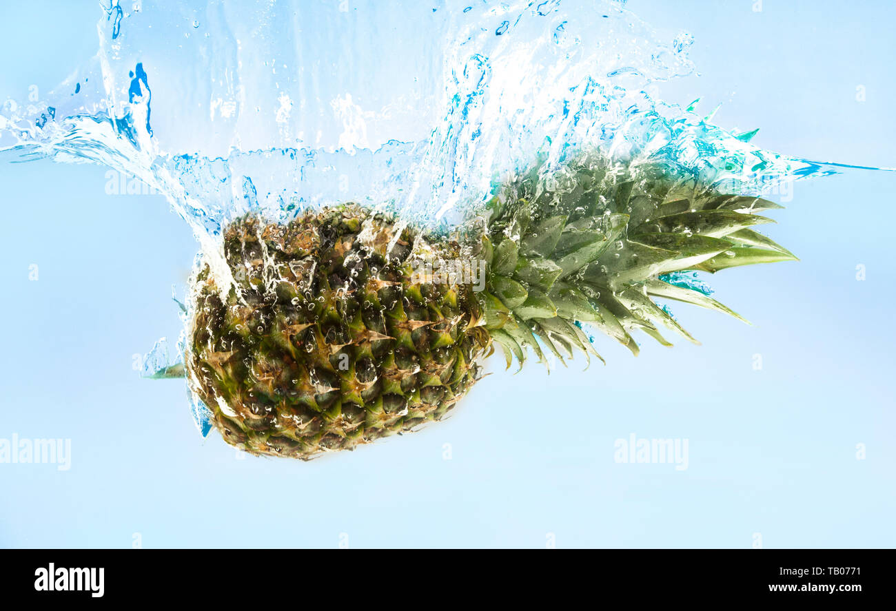 Ananas frais mûrs tombent dans l'eau avec splash Banque D'Images