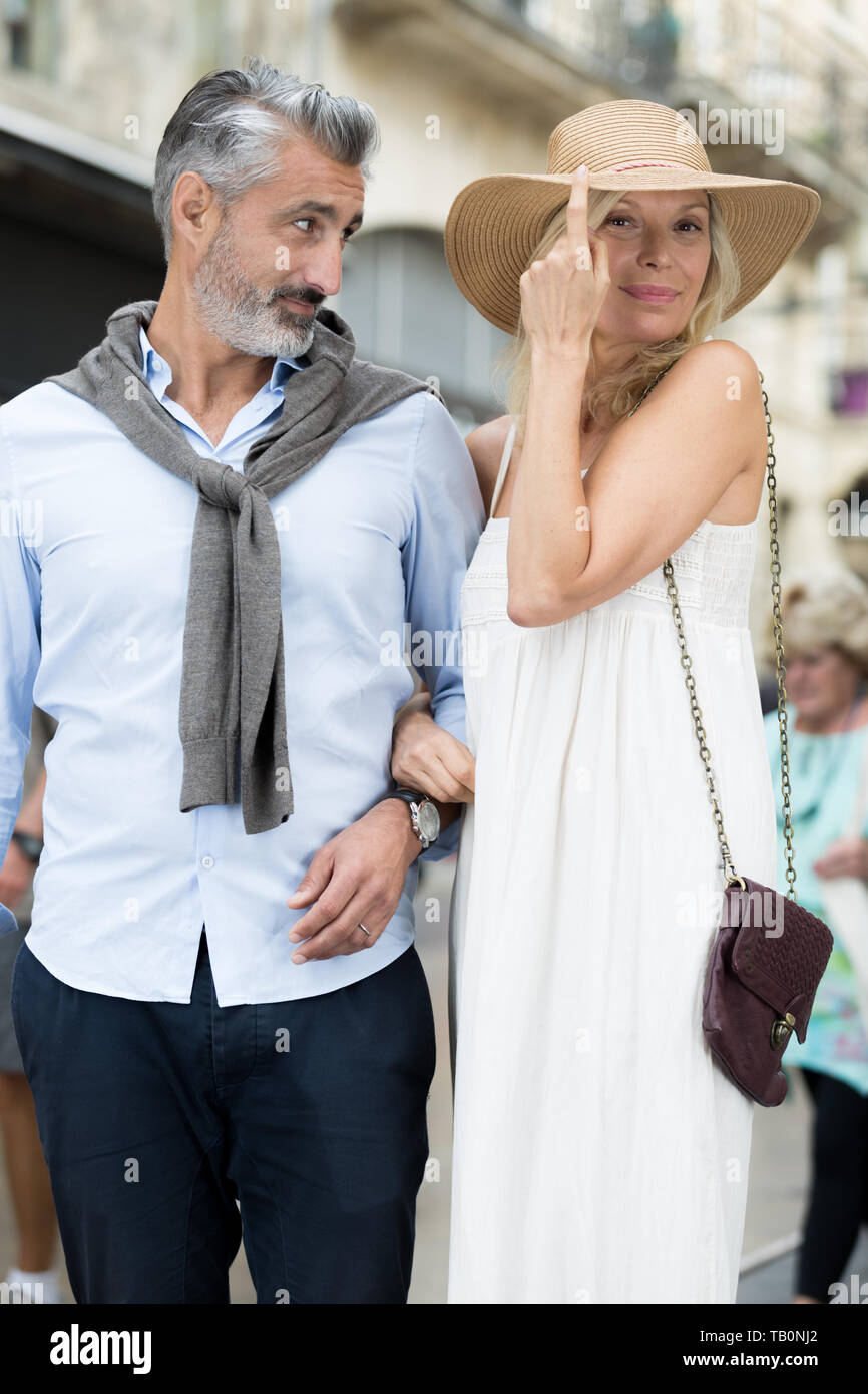 Senior couple in city street woman tipping son chapeau Banque D'Images