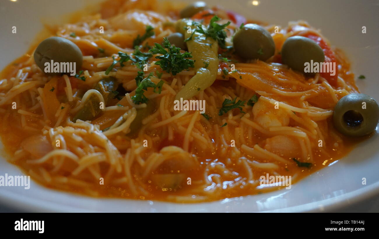 Close up de cheveux d'ange de la plaque à la sauce tomate aux olives vertes et le persil et un chili vert sur une assiette blanche. La ville de Mexico. Banque D'Images