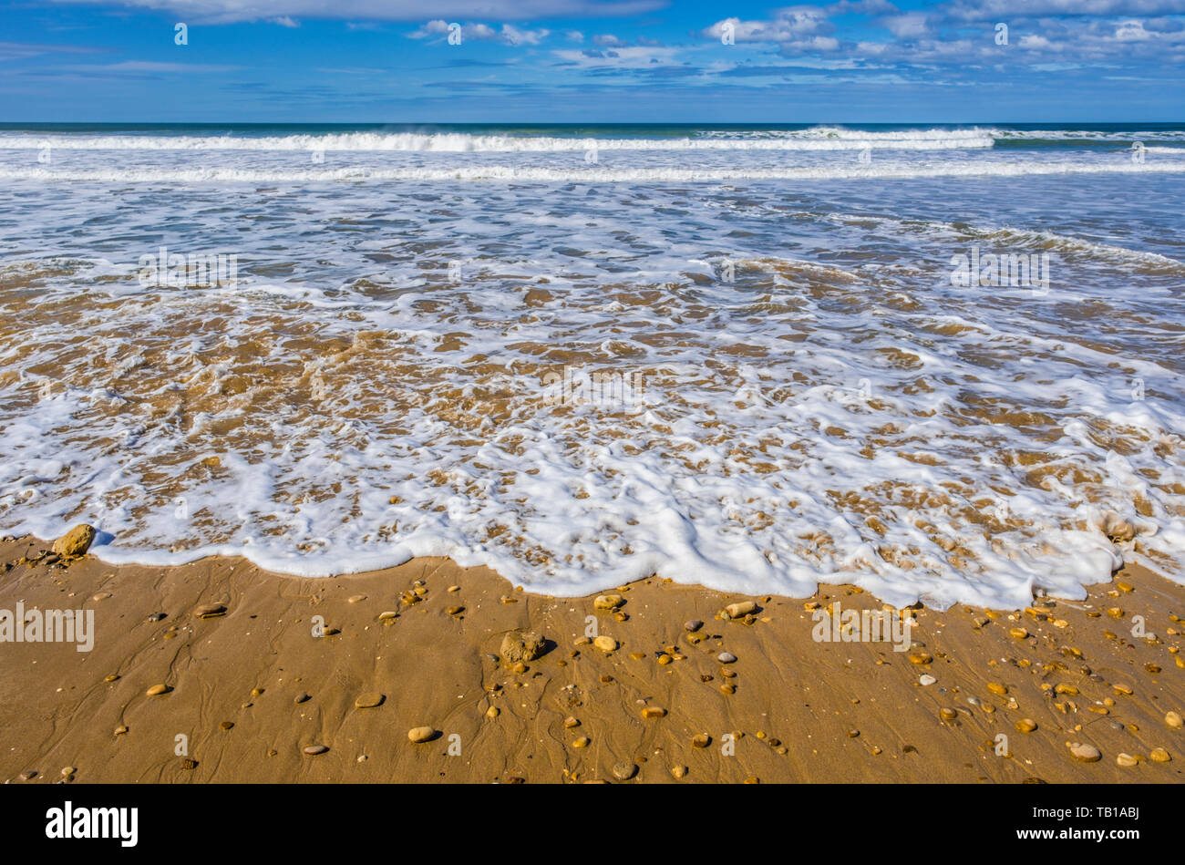 Des eaux vives précipitant s'inondent sur une plage de sable Banque D'Images