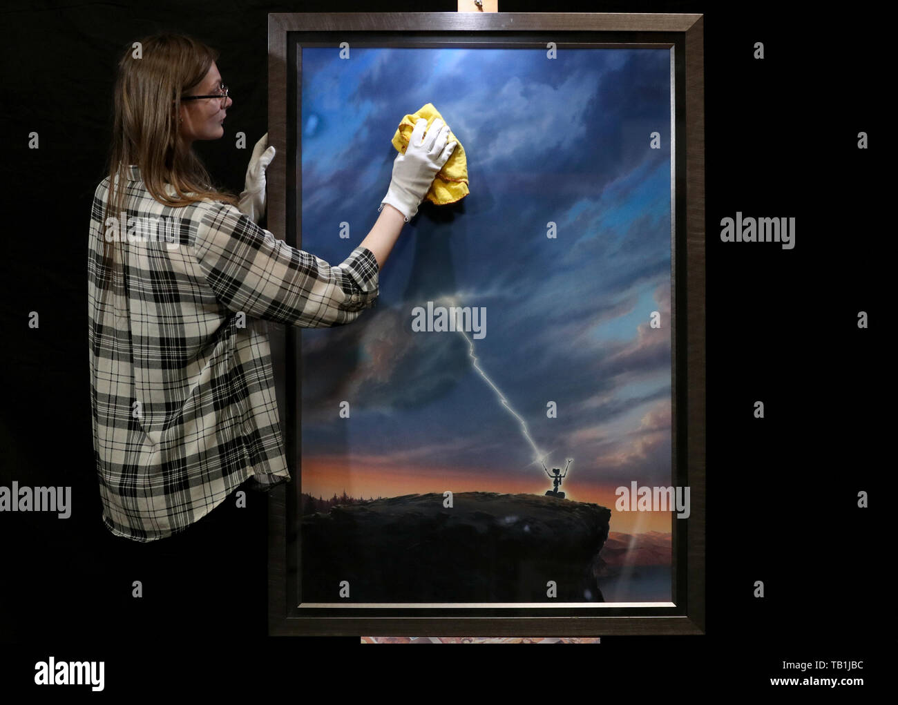 Un employé du magasin Prop nettoie la face d'une œuvre d'art originale d'une affiche pour la conception du film 1986 « court-circuit' par l'artiste John Alvin, lors d'un aperçu de la prochaine vente aux enchères d'affiches de cinéma à la prop Store siège social près de Rickmansworth. Banque D'Images