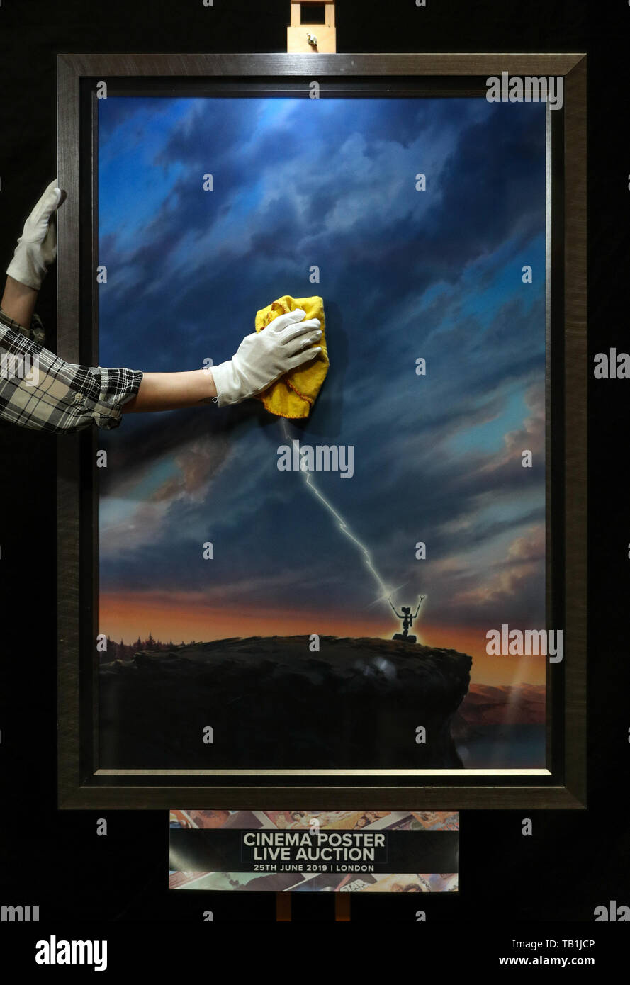 Un employé du magasin Prop nettoie la face d'une œuvre d'art originale d'une affiche pour la conception du film 1986 « court-circuit' par l'artiste John Alvin, lors d'un aperçu de la prochaine vente aux enchères d'affiches de cinéma à la prop Store siège social près de Rickmansworth. Banque D'Images