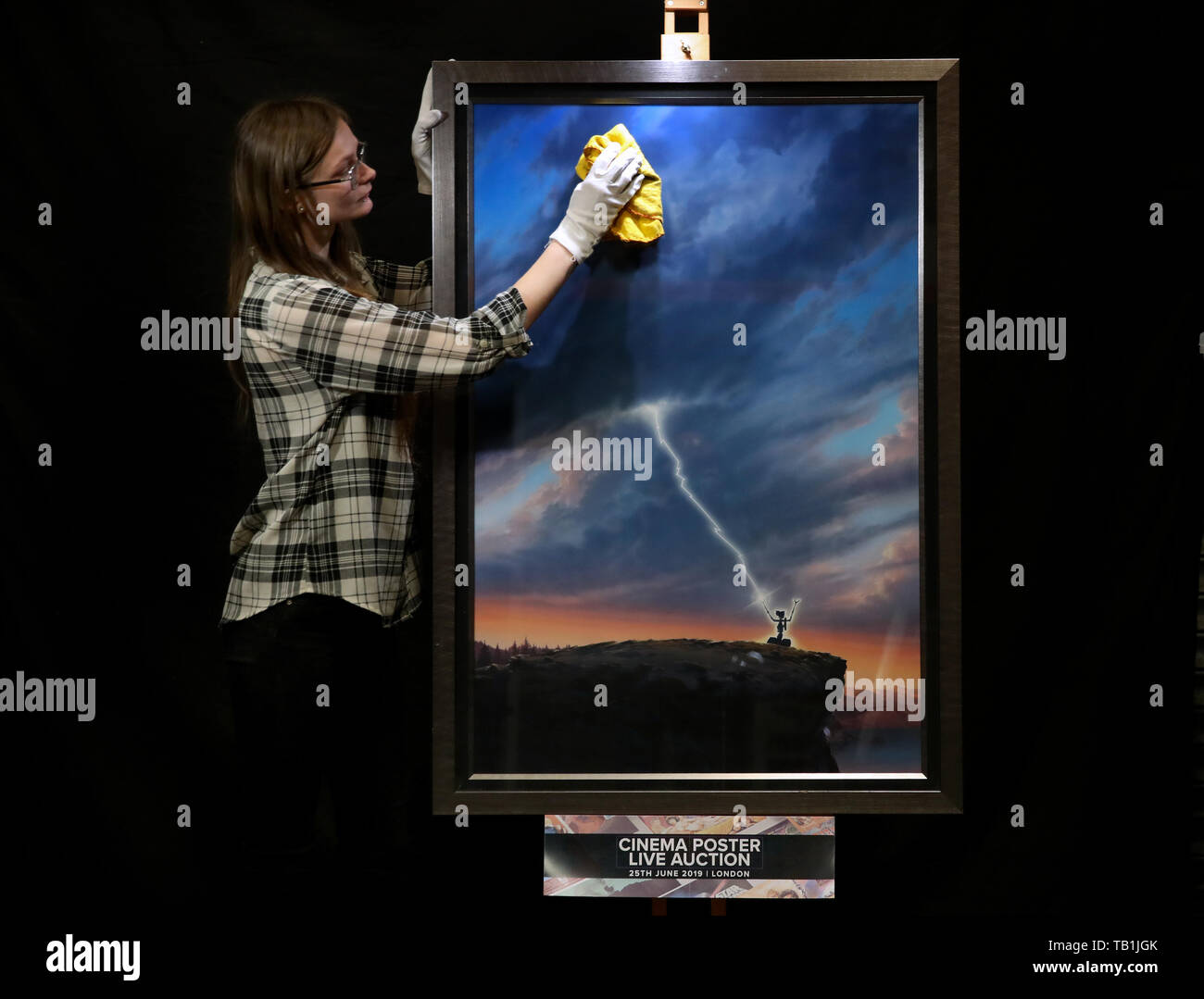 Un employé du magasin Prop nettoie la face d'une œuvre d'art originale d'une affiche pour la conception du film 1986 « court-circuit' par l'artiste John Alvin, lors d'un aperçu de la prochaine vente aux enchères d'affiches de cinéma à la prop Store siège social près de Rickmansworth. Banque D'Images