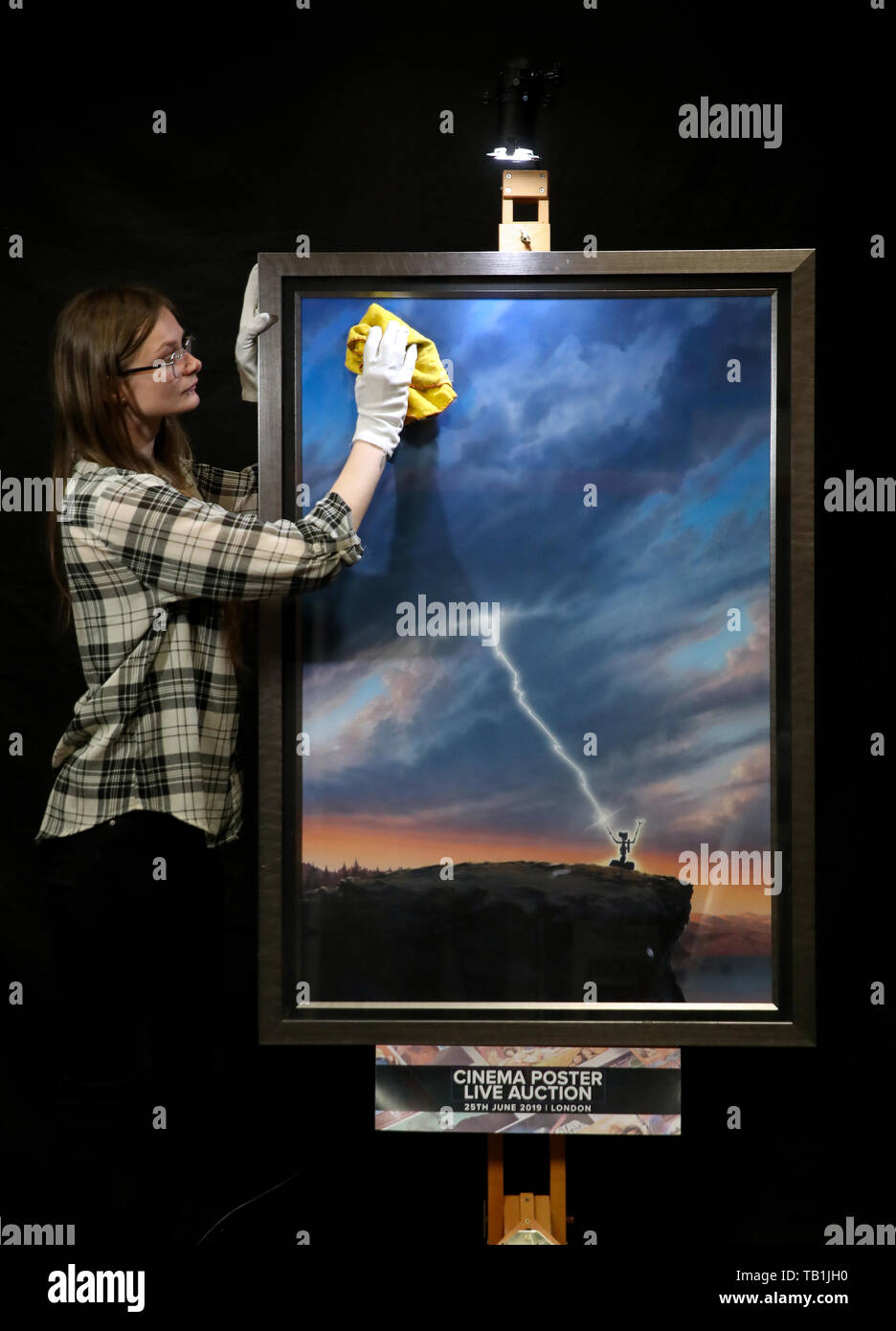 Un employé du magasin Prop nettoie la face d'une œuvre d'art originale d'une affiche pour la conception du film 1986 « court-circuit' par l'artiste John Alvin, lors d'un aperçu de la prochaine vente aux enchères d'affiches de cinéma à la prop Store siège social près de Rickmansworth. Banque D'Images