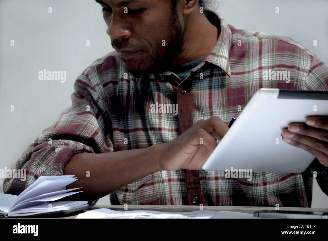 Un jeune homme noir le travail et les études holding laptop pen et à faire leurs devoirs Banque D'Images