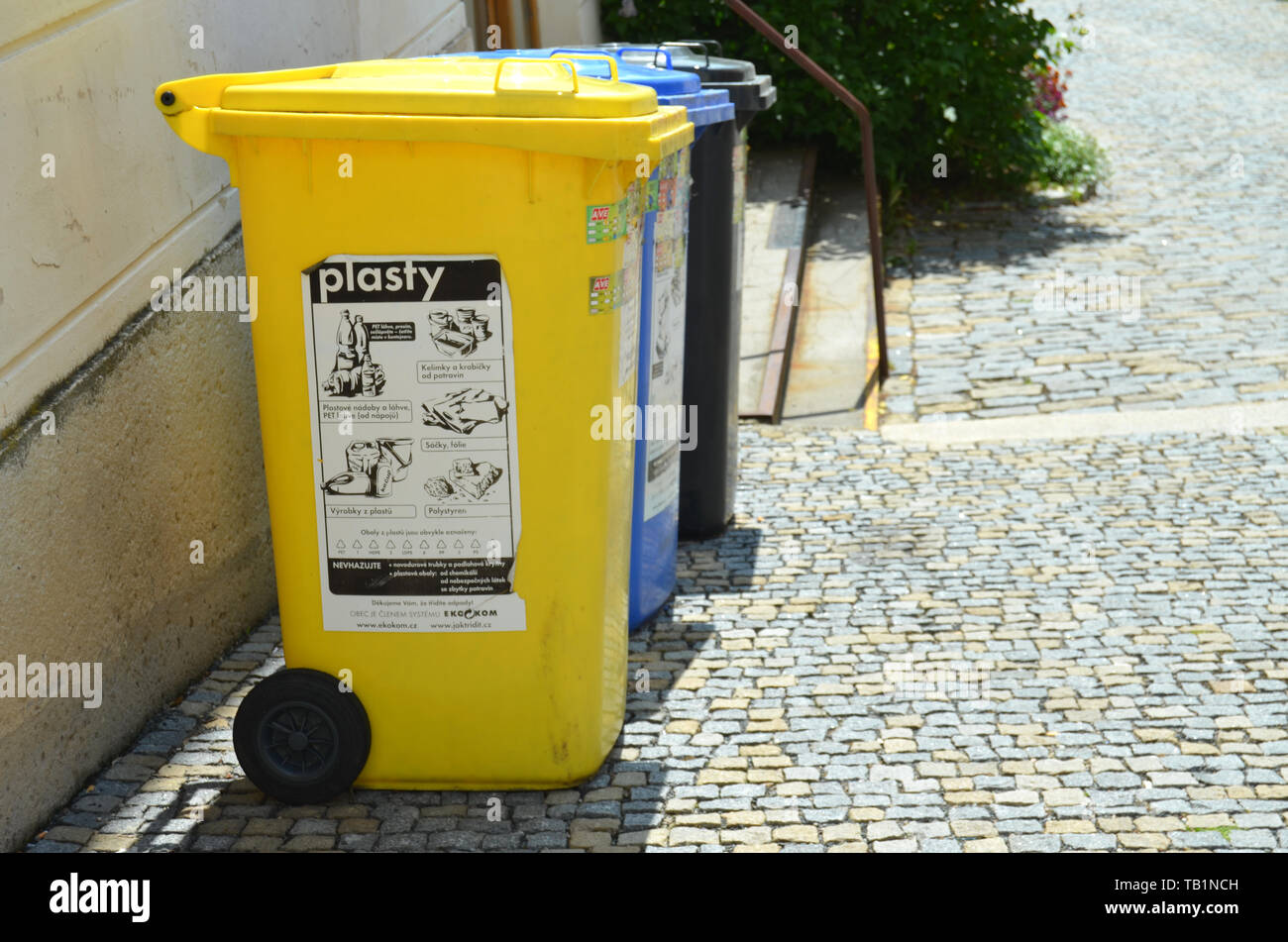 Les déchets plastiques poubelles pour le recyclage et le tri des déchets sur une vieille rue avec chaussée de pierre avec des messages sur la République tchèque. Banque D'Images