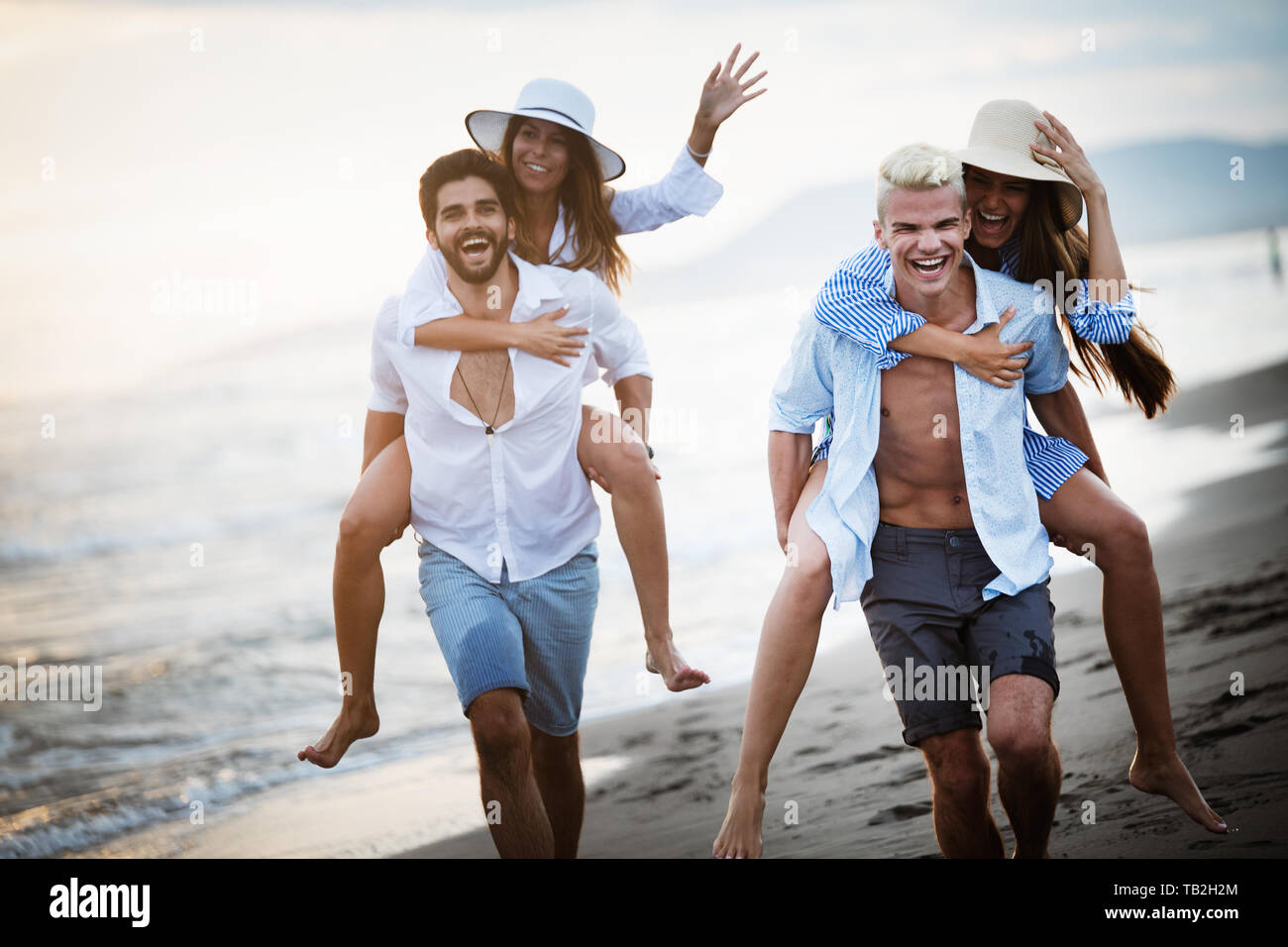 Les amis s'amusant sur la plage sous le coucher du soleil du soleil. Banque D'Images