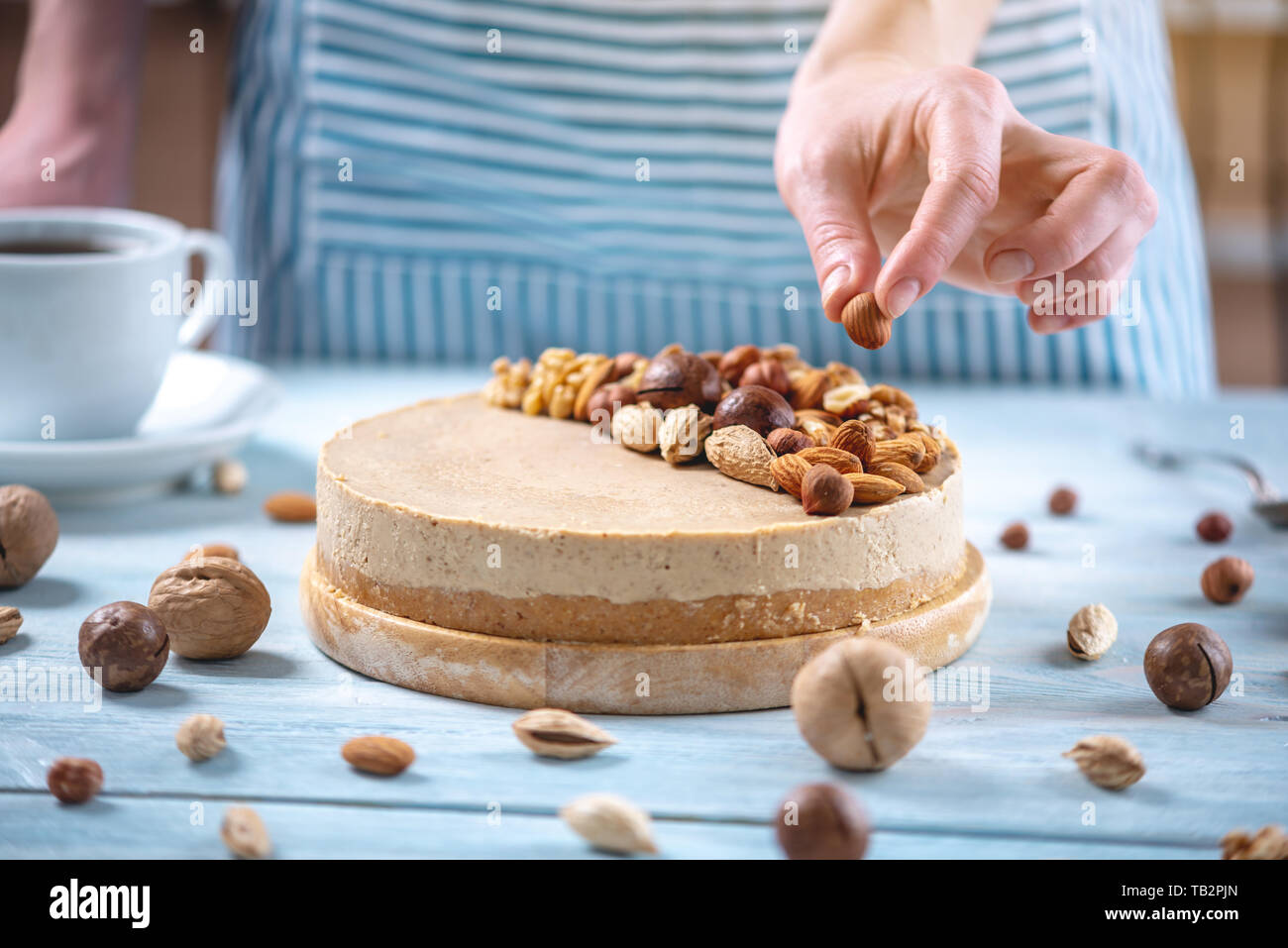 Caramel Noisette Gateau Au Fromage Avec Garniture De Noix Amandes Noisettes Et Noix Macadamia Sur Un Fond De Bois Patissier Dans Un Tablier Bleu Decore Ho Photo Stock Alamy