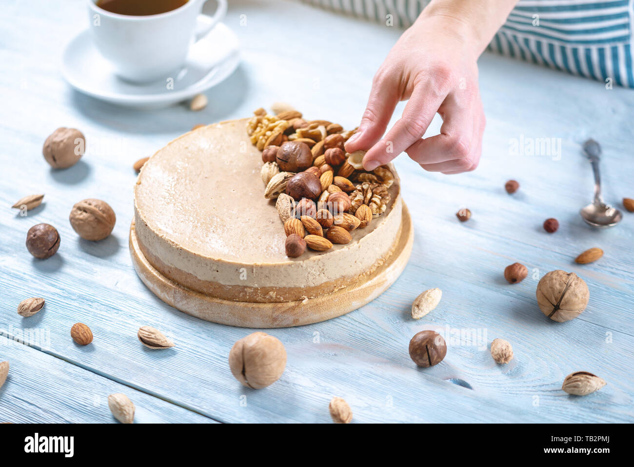 Caramel Noisette Gateau Au Fromage Avec Garniture De Noix Amandes Noisettes Et Noix Macadamia Sur Un Fond De Bois Patissier Dans Un Tablier Bleu Decore Ho Photo Stock Alamy