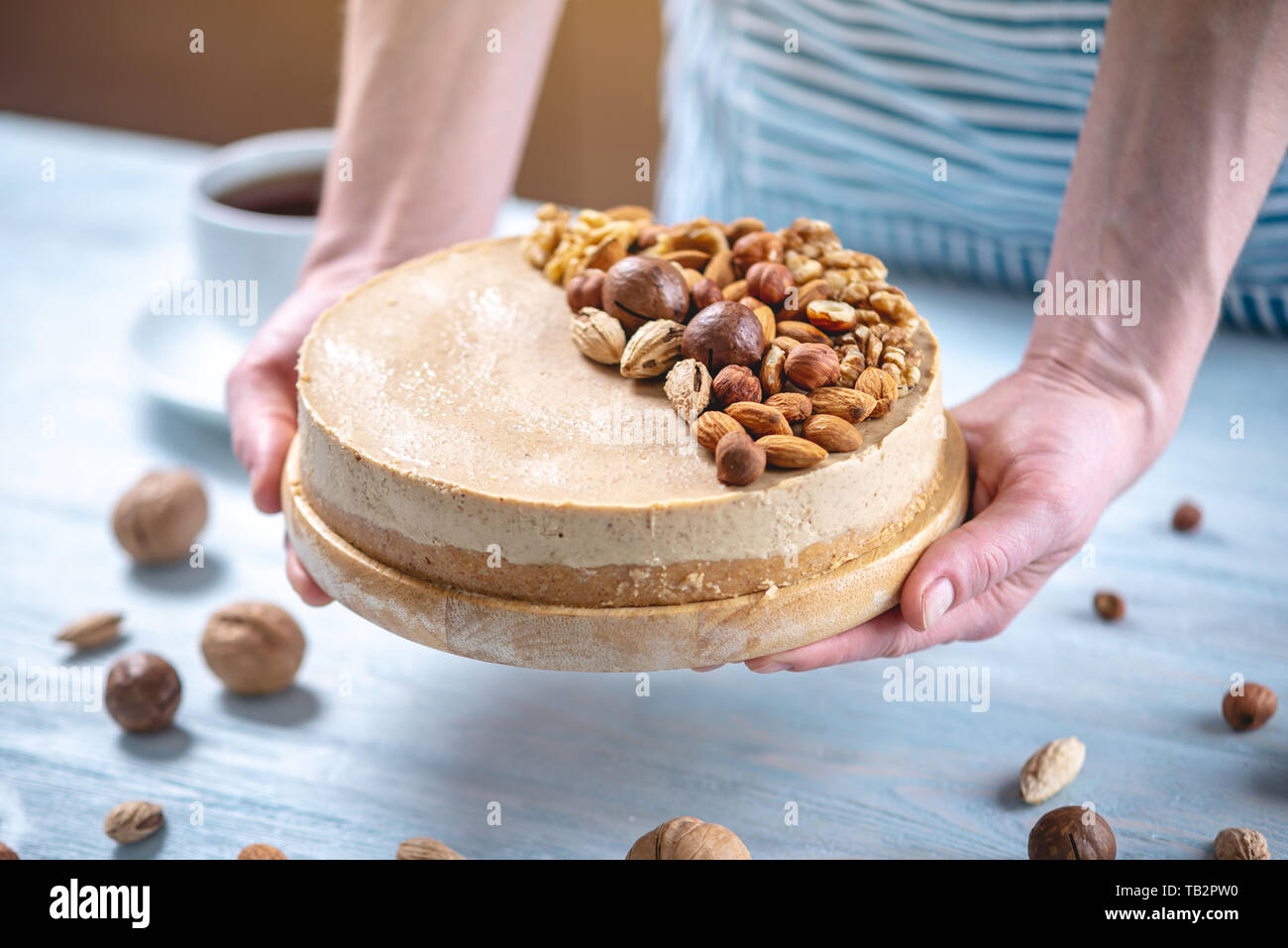 Caramel Noisette Gateau Au Fromage Avec Garniture De Noix Amandes Noisettes Et Noix Macadamia Sur Un Fond De Bois Patissier Dans Un Tablier Bleu Decore Ho Photo Stock Alamy