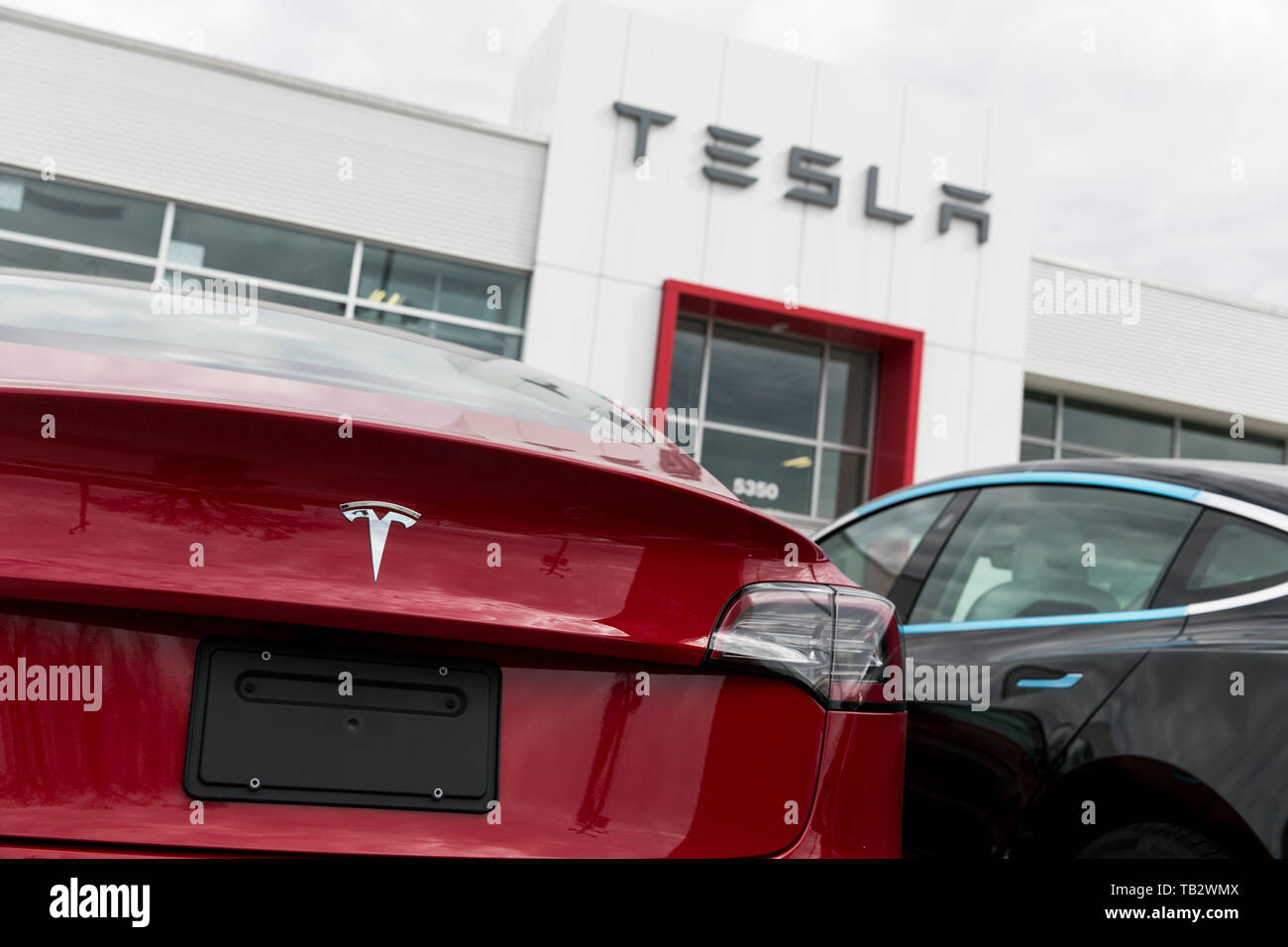 Un logo affiche à l'extérieur d'un concessionnaire de voiture Tesla avec le modèle 3 et le modèle S voitures dans le lot à Montréal, Québec, Canada, le 21 avril 2019. Banque D'Images