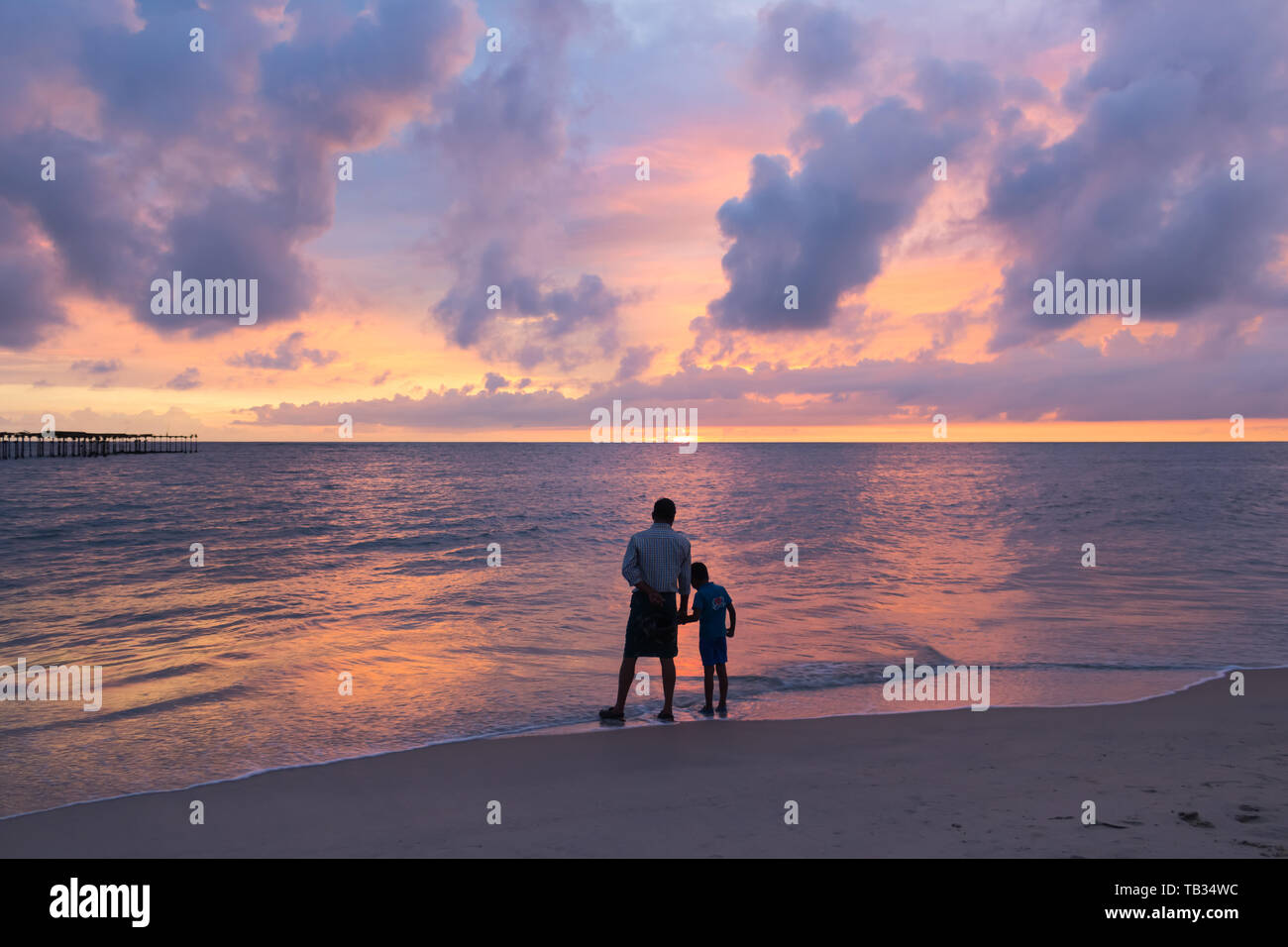 Père et fils en regardant le coucher du soleil spectaculaire à Alleppey Alappuzha Beach au Kerala Inde Banque D'Images