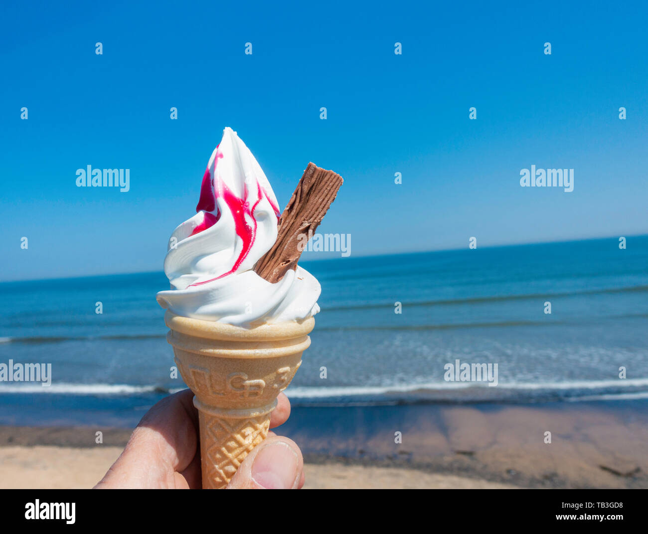 Quatre-vingt-dix neuf cornet de crème glacée à la framboise contre blues ciel et mer. UK Banque D'Images