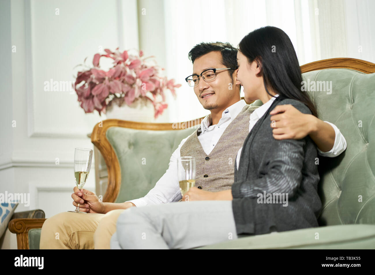 Les jeunes asiatiques aimant couple sitting on couch talking chatting at home Banque D'Images