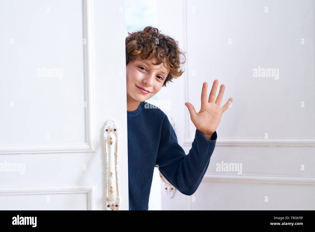 Peu caucasian boy ouvre la porte et les vagues part dire bonjour Banque D'Images